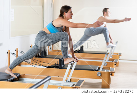 Girl doing stretching exercises on reformer in pilates studio 124358275
