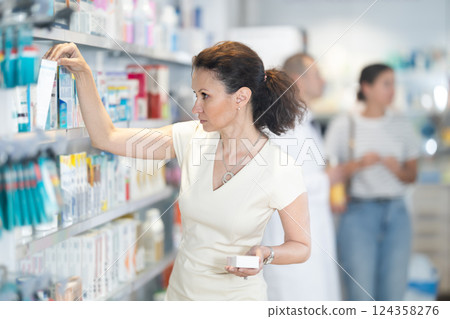 Adult woman chooses medicine in pharmacy 124358276