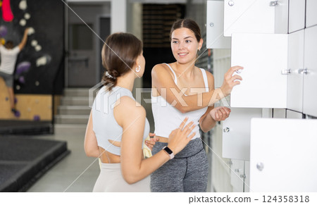 Two young women talking in locker room 124358318