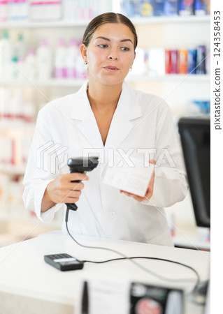 Young female pharmacist scanning barcode on sold medicine box 124358453
