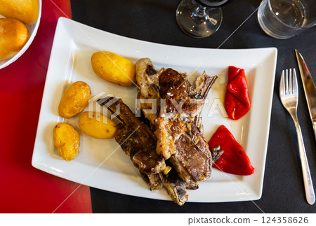 Fried lamb served with potatoes and peppers 124358626