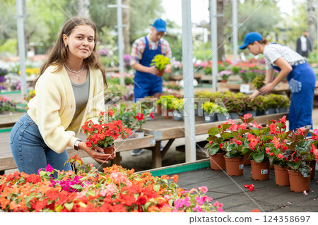 Girl choosing blooming Impatiens Walleriana in pots at garden center Girl choosing blooming Impatiens Walleriana in pots at garden center 124358697