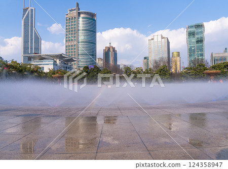 Square fountain and city skyline under blue sky and white clouds 124358947
