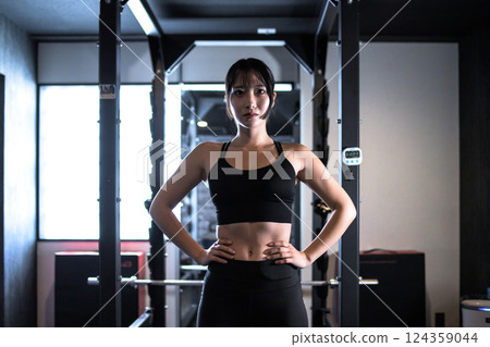 A cool woman standing confidently in front of a mirror, working out at the gym, standing in a pose, muscle training girl, natural color 124359044