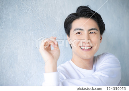 Close-up of a young man stretching against a light blue background. A refreshing image of beauty and beauty. 124359053
