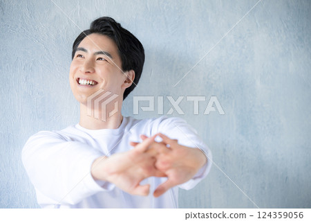 Close-up of a young man stretching against a light blue background. A refreshing image of beauty and beauty. 124359056