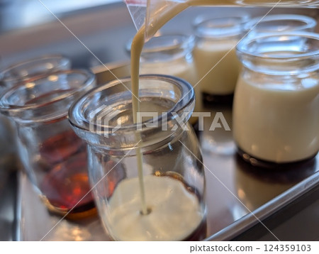 Pouring pudding liquid into a glass container Pouring pudding liquid into a glass container 124359103