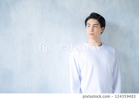 Young handsome man in t-shirt looking up against light blue background 124359483