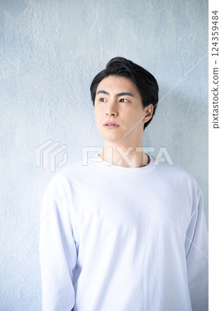 Young handsome man in t-shirt looking up against light blue background Young handsome man in t-shirt looking up against light blue background 124359484