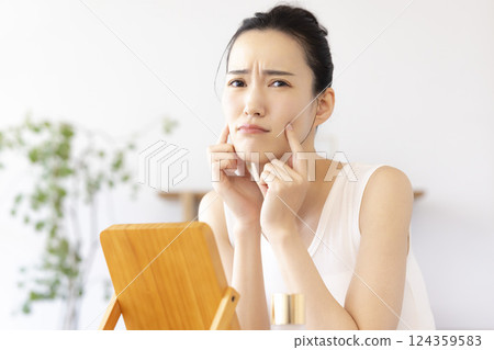 Lifestyle: A woman doing skin care while looking in the mirror 124359583
