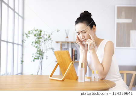 生活方式：一位女士一邊照鏡子一邊進行皮膚護理 124359641
