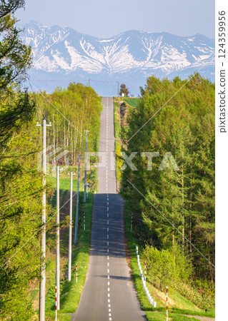 A road leading to Jyujitsu Hills overlooking the Daisetsuzan mountain range 124359956