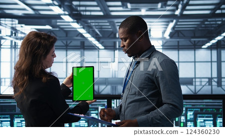 Engineers using green screen tablet in data center, checking infrastructure reliability, writing in clipboard. Workers using mockup device in server room, managing server virtualization, camera B 124360230