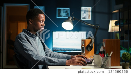 Black developer feeling exhausted and trying to meet task deadline, working hard to finish report in time and dealing with a headache. African american guy being under stress with pressure. Camera A. 124360366