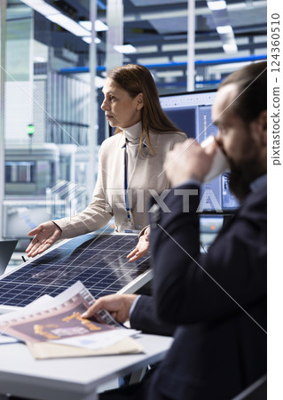 Photovoltaics factory industrial production managers looking over schematics, planning work on facility floor. Solar panels manufacturing plant engineers design assembly lines, looking over blueprints Photovoltaics factory industrial production managers looking over schematics, planning work on facility floor. Solar panels manufacturing plant engineers design assembly lines, looking over blueprints 124360510