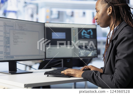 Programmer in photovoltaics facility using PC program to diagnose malfunctioning systems. African american woman coding at computer desk in solar panels manufacturing plant, reducing downtime 124360528