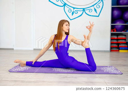 Woman practicing advanced yoga pose on a purple mat  124360675