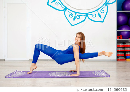 Flexible woman performing an advanced yoga arm balance pose  124360683