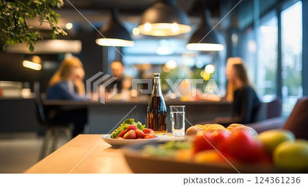 Table with fresh fruits, water glass, and beverage in a modern dining area with blurred background 124361236
