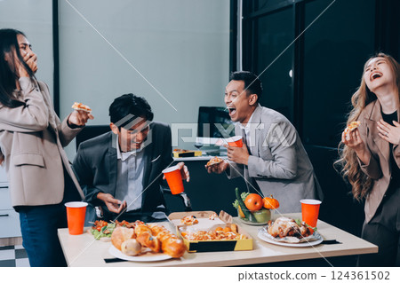 Asian office colleagues and friends enjoy a daytime BBQ with pizza and beer, celebrating Halloween and cheering for their favorite soccer team, creating a lively atmosphere filled with joy. 124361502