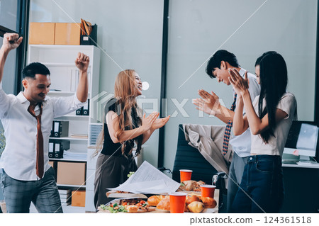 Asian office colleagues and friends enjoy a daytime BBQ with pizza and beer, celebrating Halloween and cheering for their favorite soccer team, creating a lively atmosphere filled with joy. 124361518