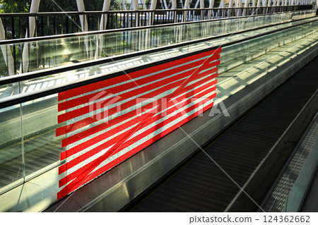 adhoc repair for Cracked or broken glass wall of public Automatic escalator walkway. Red tape Repair to conceal broken glass wall corridor.  124362662
