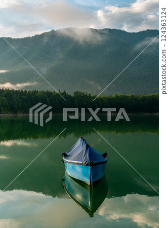 Fishing boat on Lake Sylvenstein and the mountain reflection in the water 124363124