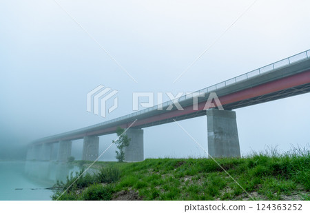 Bridge over Sylvenstein lake on a foggy morning, side view from under the bridge Bridge over Sylvenstein lake on a foggy morning, side view from under the bridge 124363252