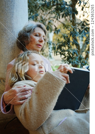 Grandmother and Granddaughter Reading Together Outside 124363265