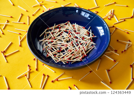 Matches in dark blue bowl over yellow background Matches in dark blue bowl over yellow background 124363449