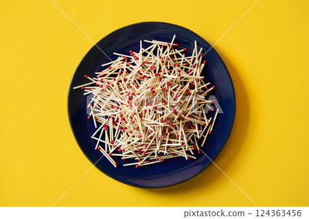 Matches in dark blue plate over yellow background Matches in dark blue plate over yellow background 124363456