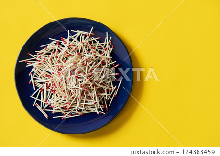 Matches in dark blue bowl over yellow background 124363459