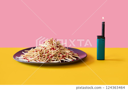 Pile of wooden matches on plate with lighter over pink yellow background. 124363464