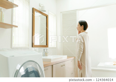 Middle-aged woman looking at the mirror in the bathroom 124364014