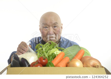 A smiling old man packing rice and vegetables into cardboard boxes 124364252