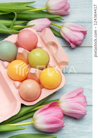 Pastel colored easter eggs and pink tulips creating festive border on wooden table Pastel colored easter eggs and pink tulips creating festive border on wooden table 124364417