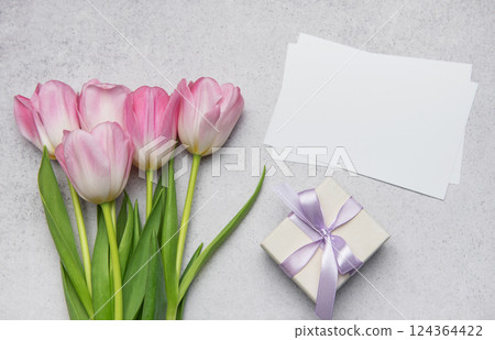 Pink tulips bouquet, gift box and blank cards creating festive composition on table Pink tulips bouquet, gift box and blank cards creating festive composition on table 124364422
