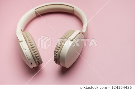 Modern wireless headphones lying on pink background Modern wireless headphones lying on pink background 124364426