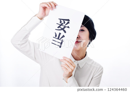 A middle-aged woman smiling happily while holding up a piece of paper that says "reasonable" 124364460