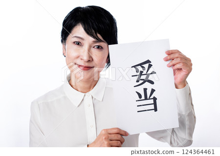 A middle-aged woman in a white shirt holding up a piece of paper that says "valid" and smiling with satisfaction A middle-aged woman in a white shirt holding up a piece of paper that says "valid" and smiling with satisfaction 124364461
