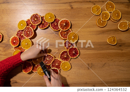 Step 2 Handmade Christmas wreath from dried orange grapefruit slices. Festive holiday preparation craft master class of creative making decor. Hands-on activities sustainable responsible holiday gift 124364532