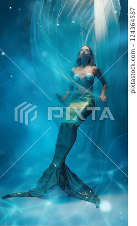 Mysterious elegant young woman, mermaid with golden tail, covered in flying fabric, floating against dreamlike ocean background 124364587