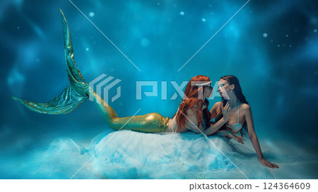 Two young passionate and tender women, enchanting mermaids gaze at each other closely, creating mystical underwater scene. Free love 124364609