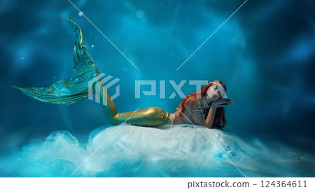 Dreamy woman as mermaid resting on floating fabric, her soft expression blending with the fluid motion of the underwater world. Dreamy woman as mermaid resting on floating fabric, her soft expression blending with the fluid motion of the underwater world. 124364611