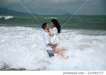 Happy young beautiful couple in love hugging in water on the beach by the sea in summer on vacation Happy young beautiful couple in love hugging in water on the beach by the sea in summer on vacation 124364717