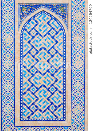 wall of Muslim mosque decorated with ceramic tiles with a traditional oriental Uzbek Islamic pattern 124364769