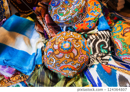 traditional festive Uzbek colorful skullcaps, scarves and fabrics at oriental bazaar in Uzbekistan 124364807