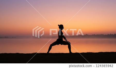 Silhouette of a person practicing yoga at sunrise by a tranquil lake 124365942