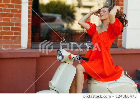 Red dress woman ride motorbike in city street 124366473