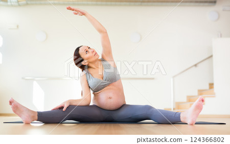 Pregnant woman is engaged in yoga. Revolved seated side angle pose or Parivrtta Upavistha Konasana 124366802